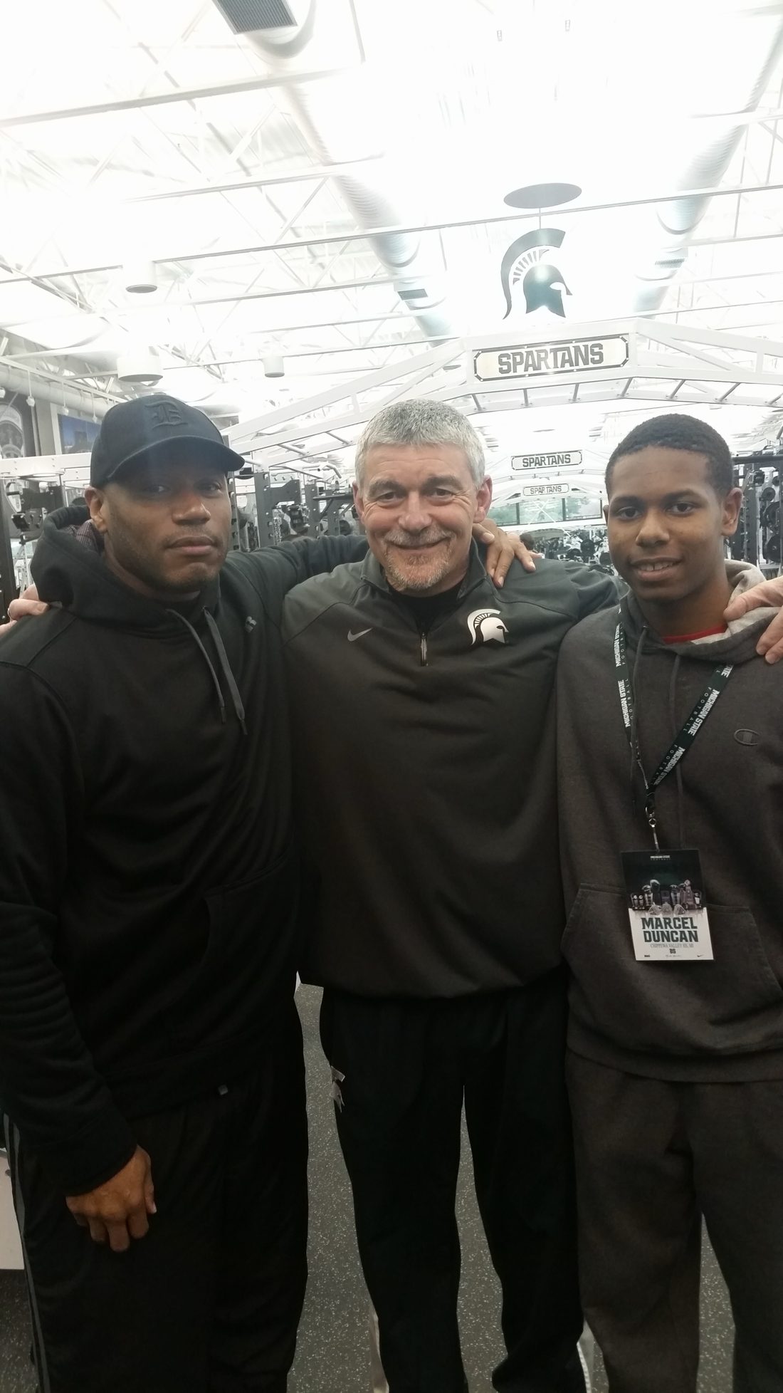 Coach Mannie with two young men in the Spartans weight room