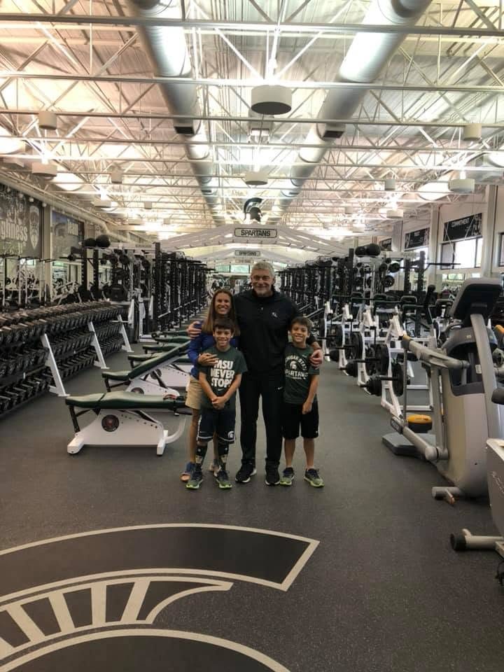 Coach Mannie with a family of visitors in the Michigan State weight room